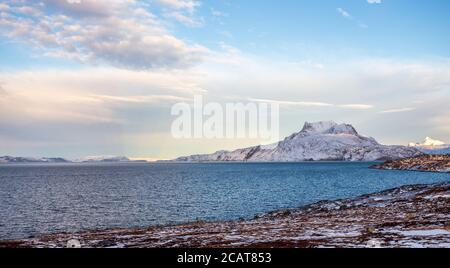 Paesaggio tundra ghiacciato con mare verde freddo e neve montagna Sermitsiaq sullo sfondo, vicino Nuuk città, Groenlandia Foto Stock