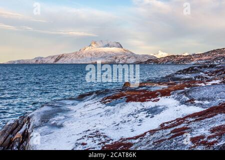 Paesaggio tundra ghiacciato con mare verde freddo e neve montagna Sermitsiaq sullo sfondo, vicino Nuuk città, Groenlandia Foto Stock