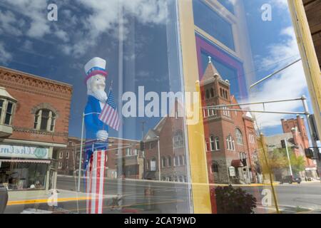 Una vetrina con una figura dello zio Sam riflette la facciata della prima chiesa Battista a Butte, Montana, sabato 8 agosto 2020. La chiesa è vuota dopo la chiusura nel dicembre 2019 dopo 133 anni di culto. Foto Stock