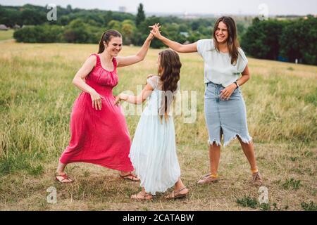 Tre ragazze sorelle che giocano al parco all'aperto. 3 ragazze, sorelle, fidanzate sul campo. Madre felice con la figlia più giovane e più grande, due bambini Foto Stock