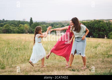 Tre ragazze sorelle che giocano al parco all'aperto. 3 ragazze, sorelle, fidanzate sul campo. Madre felice con la figlia più giovane e più grande, due bambini Foto Stock