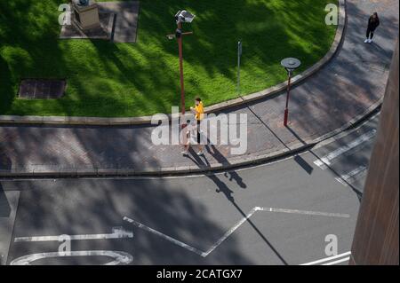 Vista sulla strada dall'alto con un paio di persone a piedi a causa delle distanze sociali in un pomeriggio di sole inverno Foto Stock