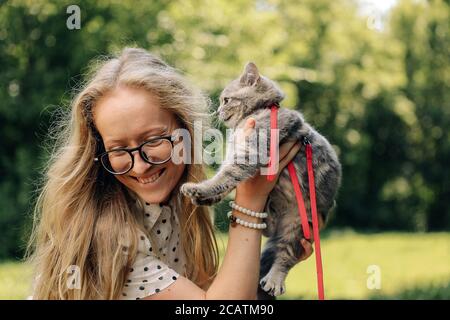 Una giovane donna bionda tiene un gattino scozzese diritto e. sorrisi Foto Stock