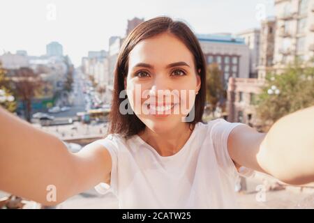 Affascinante giovane donna felice che prende selfie durante la visita turistica. Donna allegra che sorride gioiosamente, prende selfie, viaggia in Europa Foto Stock
