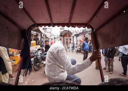 Agra / India - 22 febbraio 2020: Ritratto di uomo adulto risciò conducente sulla strada trafficata del centro di Agra Foto Stock