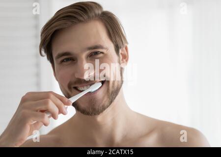 Ritratto della testa sorridente giovane uomo spazzolando i denti, igiene orale Foto Stock