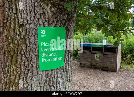 Un segno verde di allontanamento sociale del National Trust su un albero a Frensham Little Pond, un luogo di bellezza popolare in Surrey, Inghilterra sud-orientale Foto Stock