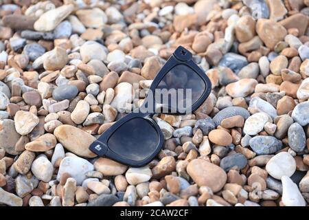 Brighton, Regno Unito. 09 agosto 2020. Un paio di occhiali da sole rotti scartati in plastica sulla spiaggia di Brighton questa mattina. Credit: James Boardman/Alamy Live News Foto Stock