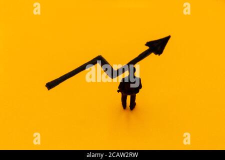 Figurina in miniatura posta come uomo d'affari davanti alla freccia ascendente del grafico, immagine di concetto di prestazioni positive Foto Stock