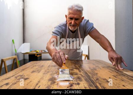 carpentiere professionista sta costruendo un tavolo di legno all'aperto officina Foto Stock