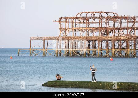 Brighton, Regno Unito. 09 agosto 2020. Un uomo si tuffa nel mare di fronte al delitto West Pier di Brighton. Oggi si prevede di essere un altro giorno caldo con temperature che raggiungono i 86 gradi fahrenheit sulla costa meridionale. Credit: James Boardman/Alamy Live News Foto Stock