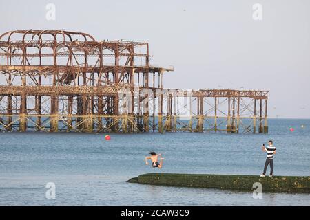 Brighton, Regno Unito. 09 agosto 2020. Un uomo si tuffa nel mare di fronte al delitto West Pier di Brighton. Oggi si prevede di essere un altro giorno caldo con temperature che raggiungono i 86 gradi fahrenheit sulla costa meridionale. Credit: James Boardman/Alamy Live News Foto Stock