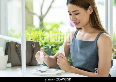 Asian attraente donna spruzzando alcool su stoviglie in ristorante per pulire ridurre l'infezione di coronavirus covid-19. Nuovo stile di vita normale al resta Foto Stock