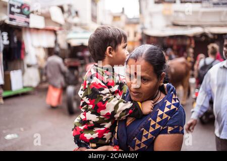 Pushkar / India - 6 marzo 2020: Ritratto candido della donna indiana che tiene il bambino che cammina in strada Foto Stock