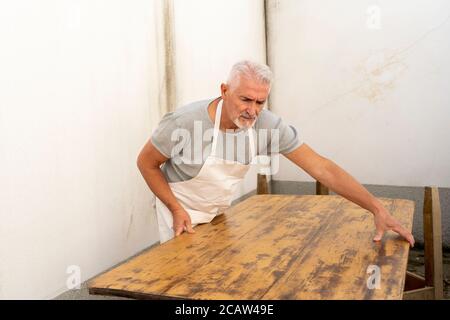 carpentiere professionista sta costruendo un tavolo di legno all'aperto officina Foto Stock