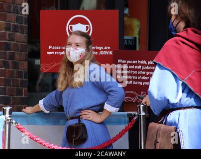 Un personale in costume che indossa maschere accoglie i turisti al Jorvik Viking Center di York. A partire dall'8 agosto, il governo britannico ha reso obbligatorio indossare maschere per il viso quando si visitano musei e gallerie. Foto Stock