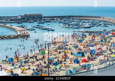 Lyme Regis, Dorset, Regno Unito. 9 agosto 2020. Regno Unito Meteo: I vacanzieri e i cercatori di sole imballano fuori la spiaggia di nuovo la domenica per crogiolarsi in un altro giorno di sole caldo bruciante mentre l'onda di calore di estate continua. I beachgoer si affollano nelle località costiere della costa meridionale per godersi il sole caldo e le temperature calde che splengono da record. Credit: Celia McMahon/Alamy Live News Foto Stock