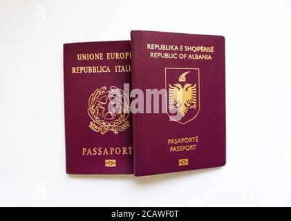 Tenendo in mano due passaporti di nazionalità diversa su sfondo bianco - Albania e Italia - imbarco, treveling e documenti Foto Stock