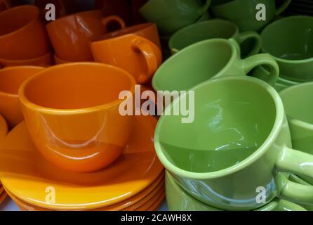 tazza in ceramica con piattino, tazze di ceramica di diversi colori in negozio Foto Stock