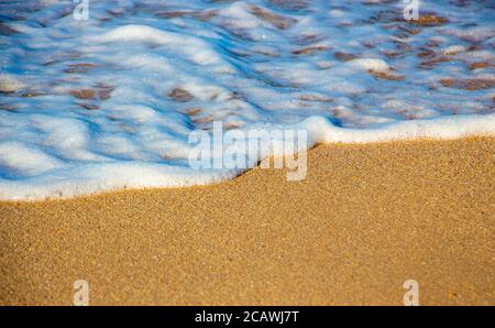 Onde e schiuma sulla sabbia, sfondo di onde sul mare Foto Stock