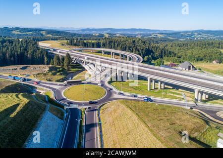 Nuova autostrada in Polonia sulla strada nazionale n. 7, E77, chiamata Zakopianka. Incrocio di cavalcavia con una rotonda, strade di scivolamento e viadotti vicino Skomielna Foto Stock