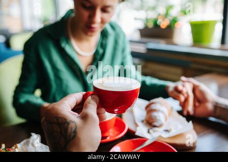 Punto di vista foto di un uomo che tiene la mano della donna su data e bere caffè Foto Stock