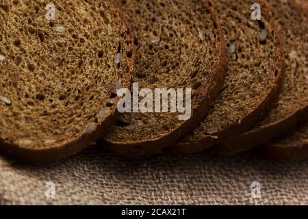 Pane di segale con semi a fette, burlap, sfondo Foto Stock