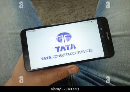 Uomo che detiene smartphone con la società Tata Consultancy Services Limited (TCS) logo Foto Stock