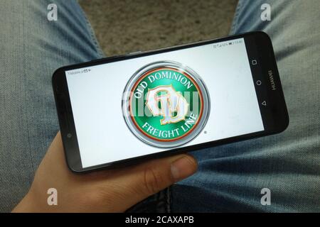 Uomo che tiene uno smartphone con il logo della società Old Dominion Freight Line Foto Stock