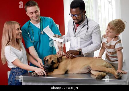 famiglia con il cane è venuto a controllare per l'esame annuale, donna di controllo. e figlio sono preoccupati per la salute del loro cane Foto Stock