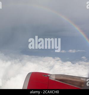 Bella vista dalla finestra dell'aeroplano e arcobaleno sul cielo durante una tempesta. Foto Stock