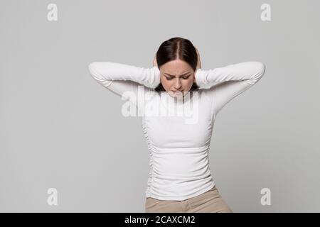 Arrabbiato stressato femmina infelice che copre le orecchie, chiudendo le orecchie con entrambe le mani, avendo problemi di mal di testa con il rumore dei vicini di cui sopra, sentire io Foto Stock