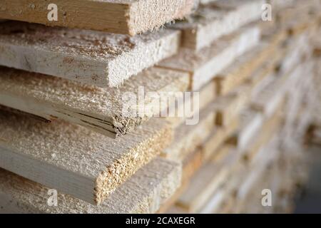 Pila di tavole di legno grezzo naturale da vicino. Deposito di legno in un'officina di falegname o ad una segheria Foto Stock