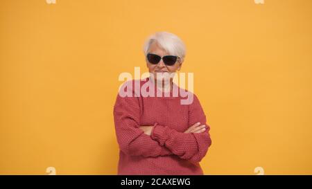 Donna anziana fresca con capelli corti e occhiali da sole grigi e mani incrociate. Isolato. Foto di alta qualità Foto Stock