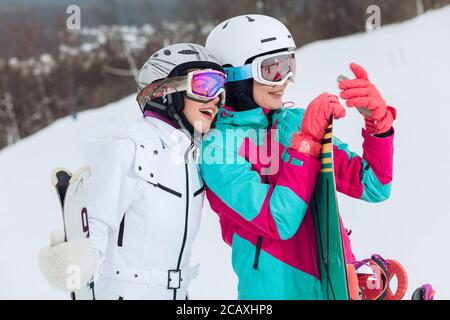 due belle donne snowboarder che prendono un selfie, primo piano vista laterale photo.sportswomen sardare un messaggio, sms mentre avendo un riposo dopo snowboard Foto Stock