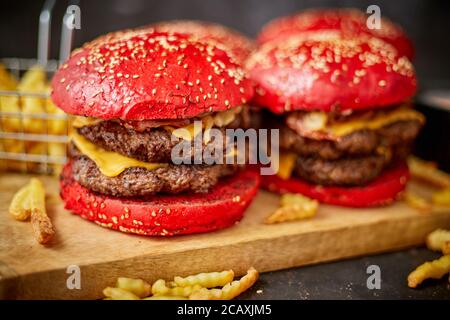 Set di quattro hamburger di formaggio becon doppio fatti in casa. Servita con patatine fritte su tavola di legno. Foto Stock