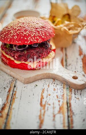 Hamburger di barbabietole di verdure fatti in casa. Panino di sesamo di colore rosso. Servito con formaggio di capra, feta Foto Stock