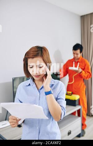 Camerata che controlla la fattura per il servizio di installazione wi-fi Foto Stock