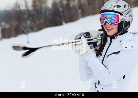 Sorridente giovane donna attiva che tiene un paio di pattini da ghiaccio, sci, primo piano foto. Copia spazio, tempo libero Foto Stock