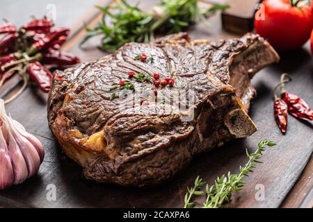 Bistecca di manzo alla griglia con spezie erbe sale pepe e aglio su tagliere di legno Foto Stock