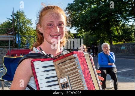 Clonakilty, West Cork, Irlanda. 9 agosto 2020. La gente di Clonakilty a West Cork è stata curata da un'improvvisata esecuzione di musica trad al sole splendente questa sera. Il Clonakilty Comhlatas Trad Music Group ha deciso di esibirsi all'aperto perché non si incontrano all'interno a causa del COVID-19. Suonando l'accodiano era Laura Sexton di 12 anni. Credit: AG News/Alamy Live News Foto Stock