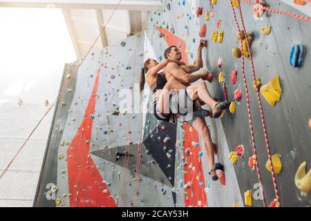 giovane uomo e donna si sono uniti a una palestra di arrampicata. vista bassa. foto a lunghezza intera. freestyle velocità Foto Stock