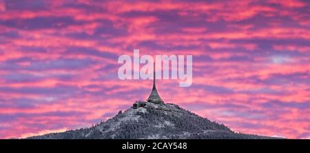 Spettacolare cielo al tramonto di Liberec con nuvole illuminate in montagna. Silhouette nera scura di cresta di montagna e torre del trasmettitore di Jested alla bott Foto Stock