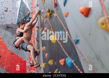 forte attraente donna e uomo che pratica l'arrampicata indoor. giovane uomo imparare a salvare le persone durante le lezioni di arrampicata. copia spazio Foto Stock