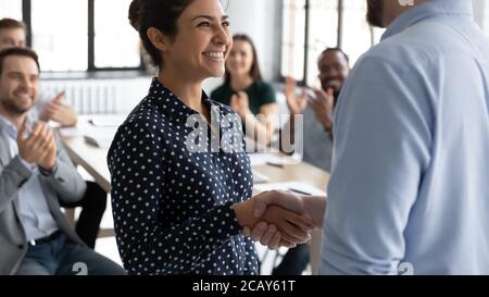 Primo piano esecutivo scuotendo sorridente mano di businesswoman indiano alla riunione Foto Stock