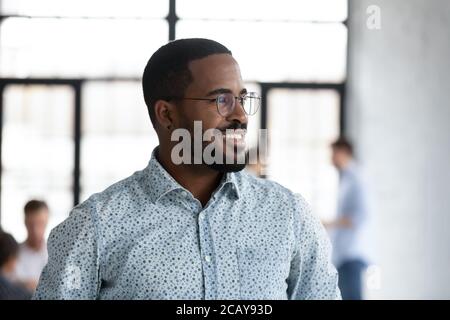 Primo piano sorridente sognante uomo d'affari afro-americano che cerca da parte Foto Stock