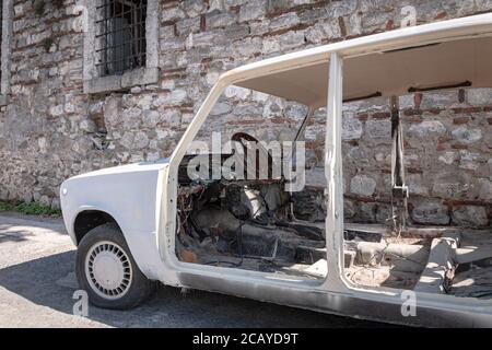 un vecchio modello di veicolo bianco rottamazione abbandonato con pannelli, portiere, sedili e selleria rimossi Foto Stock