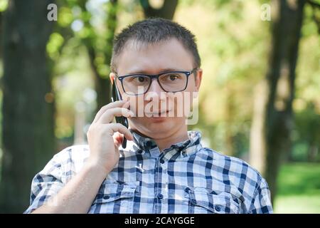 Il ragazzo sta parlando su un telefono cellulare. Tiene lo smartphone all'orecchio Foto Stock