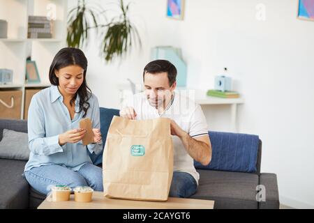 Ritratto di uomo e donna che aprono la borsa per la consegna del cibo mentre ti godi il pranzo da asporto in ufficio, copy space Foto Stock