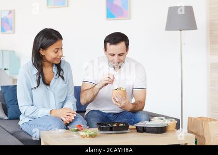 Ritratto di sorridente uomo e donna che apre contenitori per la consegna del cibo mentre si gusta il pranzo da asporto in ufficio o a casa, copia spazio Foto Stock